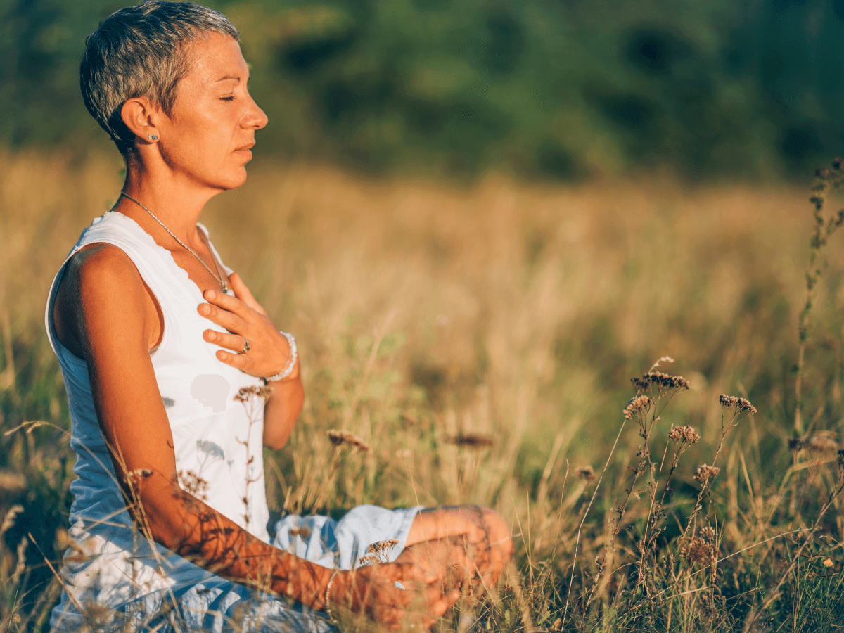 Woman meditating in nature, highlighting stress-relief secrets for women 40+