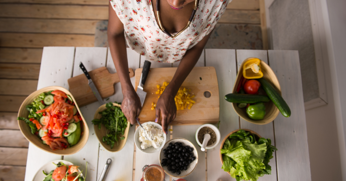 Woman 40+ in the kitchen prepping veggies, keeping meals simple, fresh, and in tune with what her body needs.